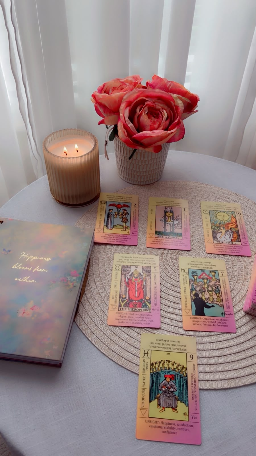 Kate Lovemore's reading space with tarot cards, a lit candle, and pink roses on a table