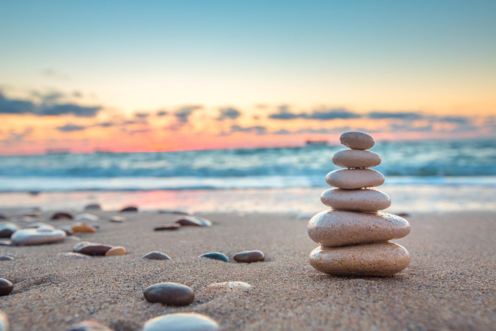 Stacked stones on a peaceful beach at sunset